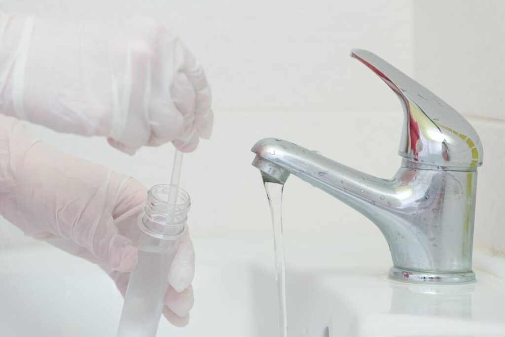 A technician getting a water sample from a faucet to test