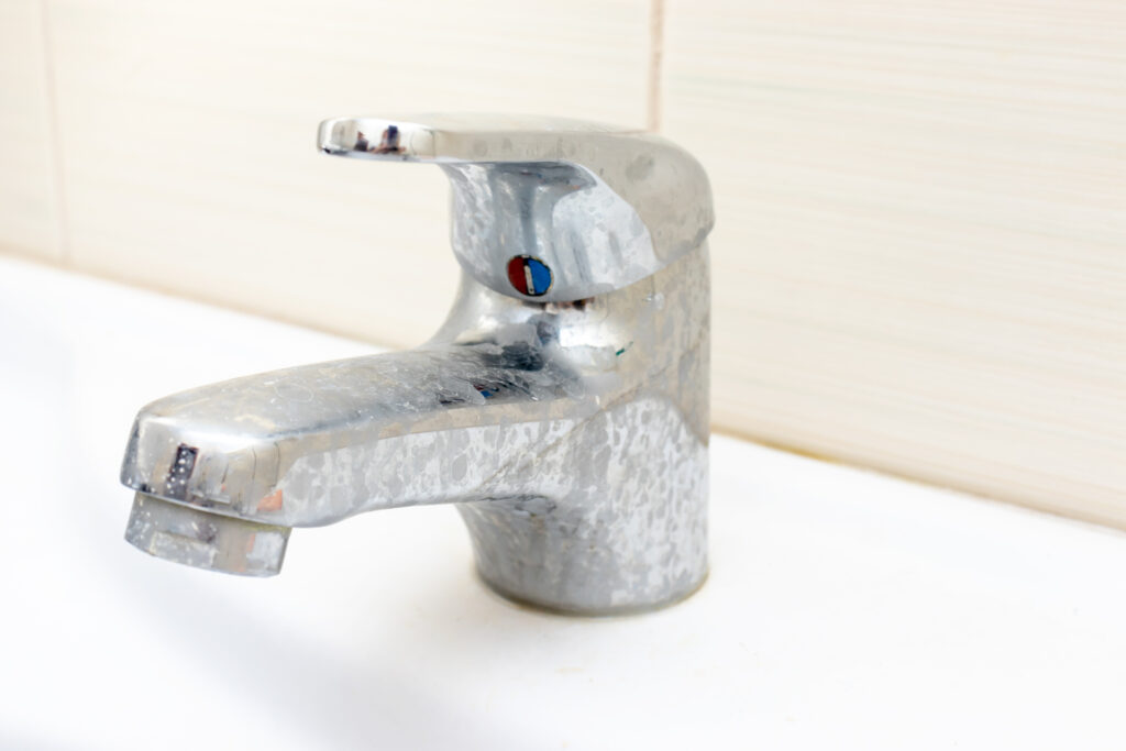 hard water limescale residue on a bathroom sink faucet