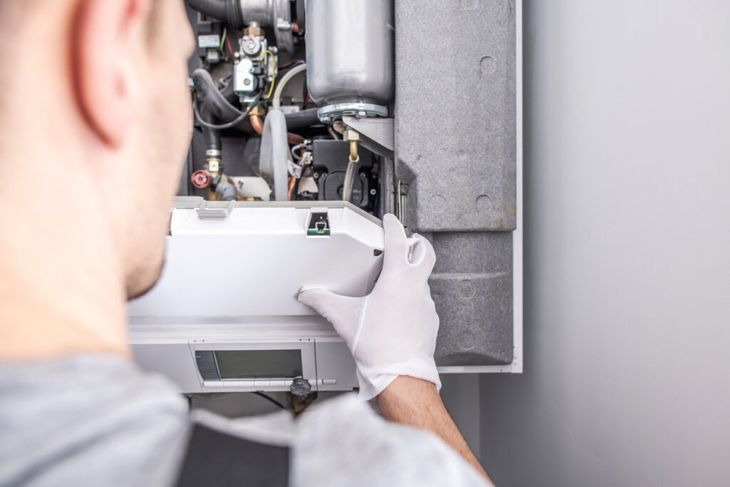 Close Up Of Caucasian Service Worker Fixing Central Heating Furnace System.